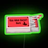 Neon matchbox sign with a witch's silhouette, glowing green in the dark.