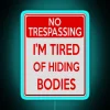 Neon sign with blue letters reading 'Tired of Hiding Bodies'