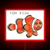 Neon sign with the word Tom Fish in bright red letters on a dark background.