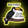 Tropical bird perched on a colorful neon sign reading "Toucan Play at That Game" in vibrant RGB hues.