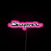 2023 Toyota GR Supra logo neon sign in pink color scheme on a city street.