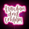Neon sign with bold, colorful lettering reading 'Transform Don't Conform'