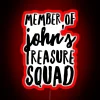 Group of friends holding up a neon sign with handwritten letters that spell out 'Treasure Squad'