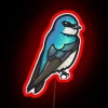 A neon sign with a tree swallow in RGB colors, set against a red background.