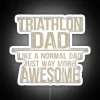 Dad in triathlon gear standing next to a neon sign with the words 'Triathlon Dad, Like A Normal Dad But Way More Awesome'".