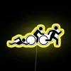 Neon triathlon sign in bright yellow colors on a city street at night.