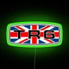 Triumph TR6 badge with Union flag on a neon sign in a green room.