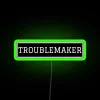 Neon sign with bold, colorful letters spelling out 'Troublemaker'