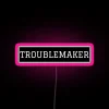 Neon pink sign reading 'Troublemaker' with bold, futuristic font.