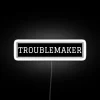 Neon sign with bold, colorful lettering reading 'Troublemaker'