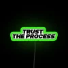 Neon sign with colorful glowing letters spelling out 'Trust The Process'