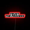 Neon sign with bold, colorful letters spelling out 'Trust The Process'