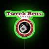 Neon sign reading Tweek Bros Coffee in vibrant green letters on a dark background.