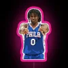 Philadelphia 76ers guard Tyrese Maxey standing in front of an RGB neon sign with pink glow.