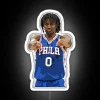 Philadelphia 76ers point guard Tyrese Maxey standing in front of an RGB neon sign with his name displayed in bold letters.