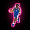 Philadelphia 76ers point guard Tyrese Maxey posing in front of an RGB neon sign with a pink glow.