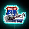 Neon sign above US-30 drag strip with blue lighting at night.