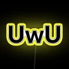 Neon "UWU" sign with colorful, glowing letters in a modern cityscape at night.