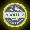 Neon sign with vibrant yellow letters spelling out VAIL COLORADO on a dark background.
