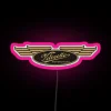 Neon pink sign with Velocette motorcycle logo in bold, colorful RGB design.