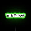 Neon sign reading "VOT-IZ-YOR-NEM" in green letters, resembling a 1980s-style voting poll indicator.