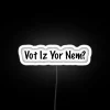 Neon sign reading 'VOT-IZ-YOR-NEM' in bold white letters against a dark background.