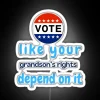 Neon sign with bold, colorful letters reading 'Vote Like Your Grandson's Rights Depend on It'