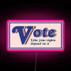 Neon sign with bold letters reading 'Vote Like Your Rights Depend On It'