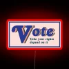 Neon sign with bold, colorful letters reading 'Vote Like Your Rights Depend On It'