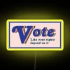 Vibrant neon sign with bold, colorful letters reading "Vote Like Your Rights Depend on It" in a stylized font.