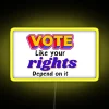 Neon sign with colorful letters spelling out 'Vote Like Your Rights Depend on It'