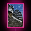 Neon-lit walkway leading to Himeji Castle at sunset.