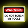 Warning neon sign with bold, yellow letters on a dark background, cautioning against touching tools.