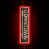Neon sign reflecting in downtown city street at night.