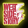 West Side Story neon sign with vibrant yellow and blue hues illuminating a city street at dusk.