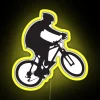 Mountain biker performing a wheelie on a neon-lit bike in a vibrant yellow color scheme.