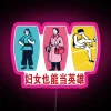 Women can be heroes neon sign with pink glowing letters on a dark background.
