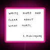 Neon sign with bold, colorful letters spelling out 'Write hard and clear about what hurts'