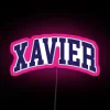 Neon sign with curved font reading Xavier College in pink and RGB colors.