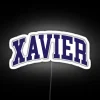 Neon sign with curved font reading Xavier College in bold, white letters against a dark background.