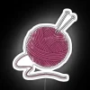 Colorful yarn ball with neon sign on a white background.