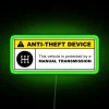 Anti-theft device warning sign with yellow background and neon green text on a 5-speed manual transmission car.