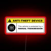 Warning sign with yellow and red lights indicating anti-theft device installation on a 5-speed manual transmission vehicle.