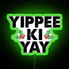 Neon sign reading 'Yippee Ki Yay' in green LED lights against a dark background.