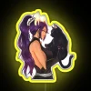 Yoruichi from Bleach standing with her black cat in front of a colorful neon sign.
