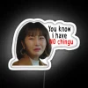 Young adult holding a neon sign reading "You know I have no ching" in a humorous expression with RGB color effects.