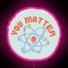 Neon sign featuring an atom design with a message of self-importance in pink hues.