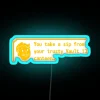 A neon sign reading "You Take A Sip" with an orange and blue glow.