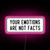 Neon sign with bold, colorful letters stating 'Your emotions are not facts'