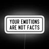 Neon sign with bold, colorful letters stating 'Your emotions are not facts'